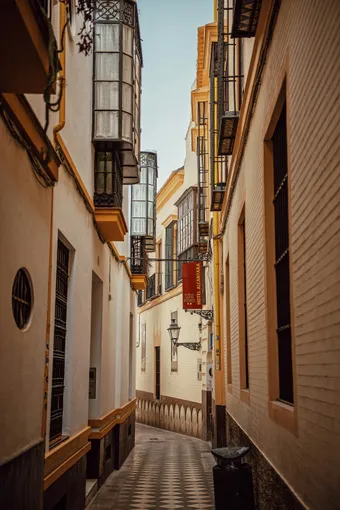 Ruelle étroite du quartier Santa Cruz à Séville, bordée de façades claires et de balcons traditionnels dans l’ancien quartier historique.