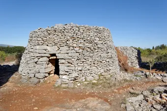 Dry-stone hut typical of the Stari Grad Plain, a testament to the ancient agricultural landscape shaped since Antiquity. Standing alone in a sun-drenched, rugged setting, it embodies the simplicity and durability of traditional Dalmatian rural architecture.