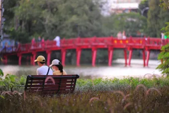 Couple enjoys a peaceful afternoon on a bench by the famous red bridge