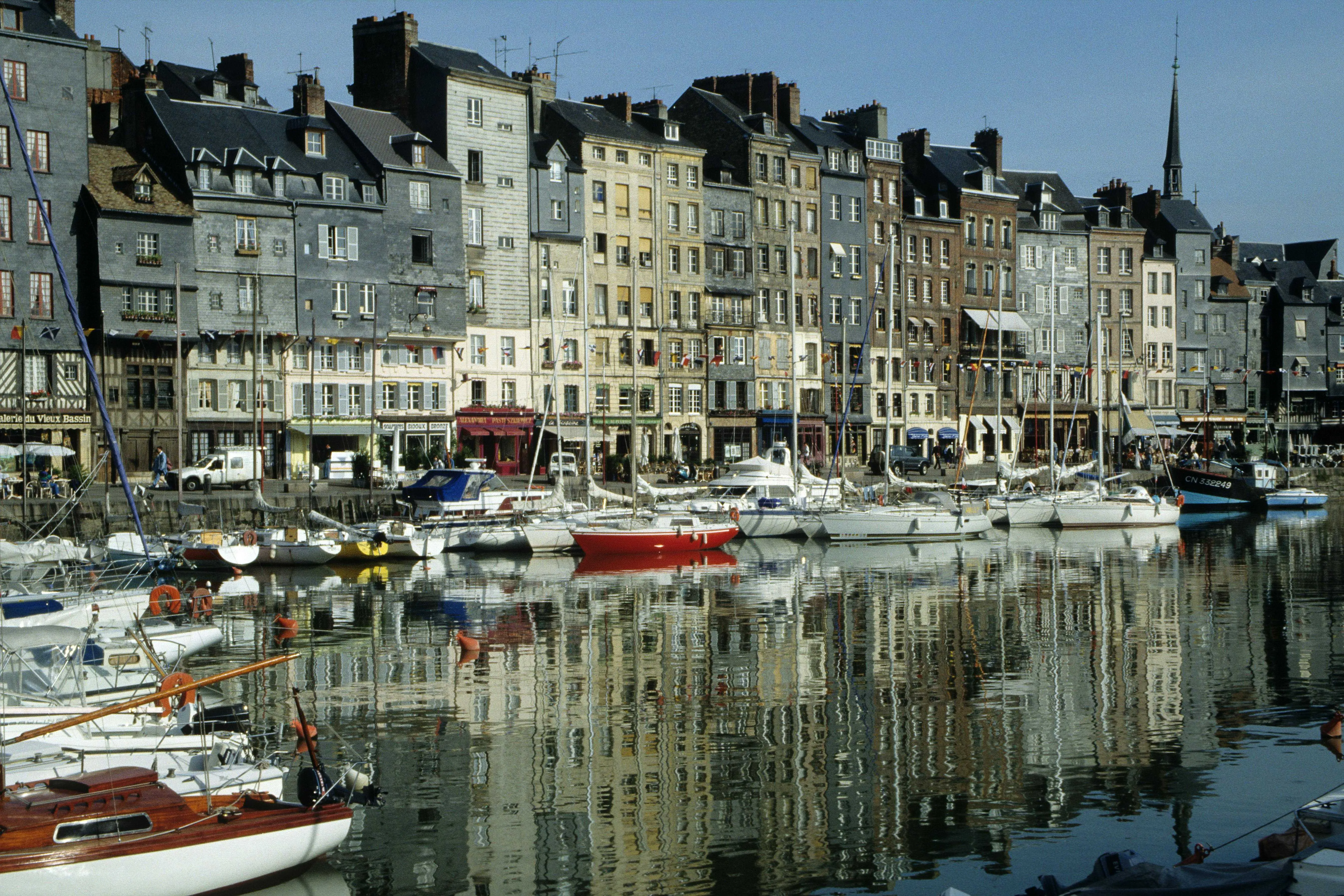 Charming boats docked by colorful historic buildings in Honfleur's Vieux Bassin, Normandy, France.