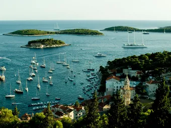 Panoramic view of the Pakleni Archipelago, off the coast of Hvar Island, where small green islets rise from turquoise waters dotted with sailboats. This iconic landscape showcases the Mediterranean charm and tranquil atmosphere of the Croatian coast.