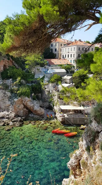 Kolorina Beach, nestled at the foot of Dubrovnik’s city walls, is an intimate cove with crystal-clear waters, framed by cliffs and Mediterranean pine trees. Located just steps from the Old Town, it is valued for its authentic atmosphere and unique views of the historic fortifications.
