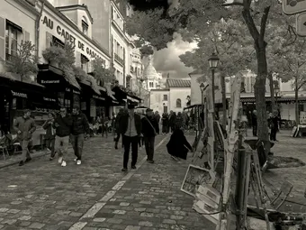 Street scene in Montmartre, Paris with Sacré-Cœur in background, bustling with people.