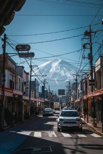 From Fujiyoshida, the view of Mount Fuji is stunning on a clear day. The mountain rises above the street, contrasting with everyday city life.