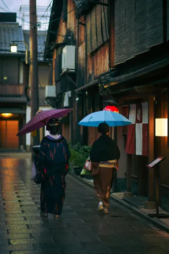 It is common to see women in kimonos carrying umbrellas in the historic streets of Kyoto, highlighting Japanese culture.