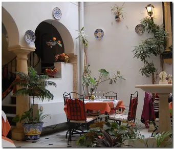 Patio fleuri d’un restaurant traditionnel dans la Judería de Cordoue, au cœur de l’ancien quartier juif. Ces patios décorés de céramiques, de plantes et de fontaines sont une caractéristique emblématique de l’architecture andalouse.