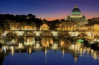 Beautiful view of Saint Peter's Basilica and St. Angelo Bridge at sunset reflecting in the Tiber River.