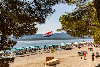 A vibrant summer scene at Zlatni Rat beach with clear blue water and beachgoers enjoying the sun.